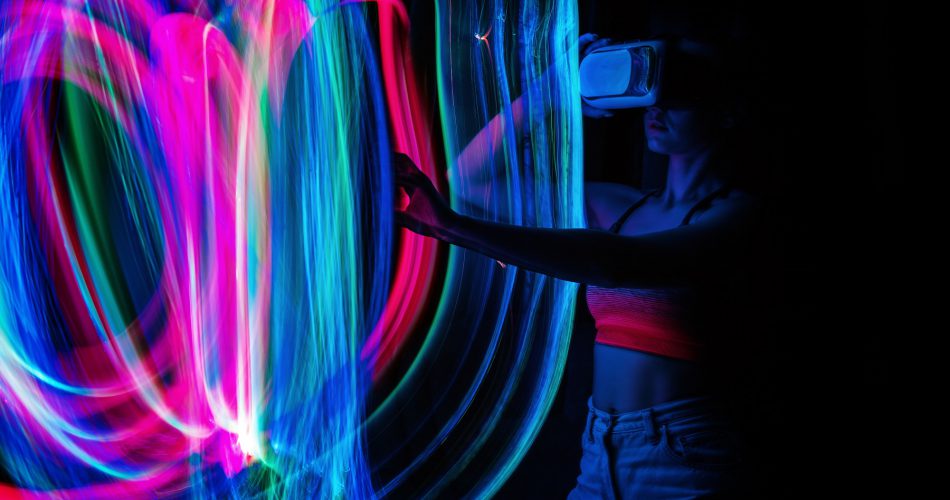 Frau mit VR-Brille ist umringt von bunten Lichtscheinen