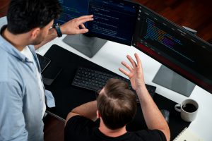 Schwachstellen-Management: IT developers discussing online software development information on pc screen, creating program coding for latest version application on website. Concept of brainstorming firmware updated. Sellable.